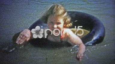 Tennessee, USA (1954): Girl enjoying a floating truck tire tube on a hot summer