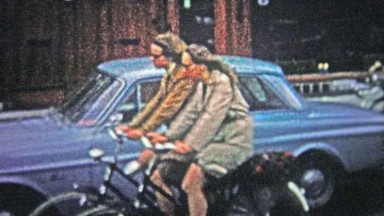 COPENHAGEN - 1966: Woman Riding Bicycle Through Urban Streets to Avoid Traffic