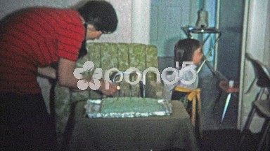 Boulder, CO. USA - 1974: Mom Lights Birthday Cake Candles as Fashionable Girl Sits Nearby