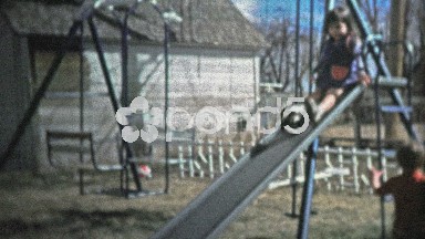 BOULDER, CO. USA - 1974: Boy going down backyard slide faceplants on landing