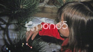 1973: Little girl and cat decorating a Christmas tree with glass ornaments.