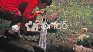 1972: Women drinking well drawn water from the end of a pipe.