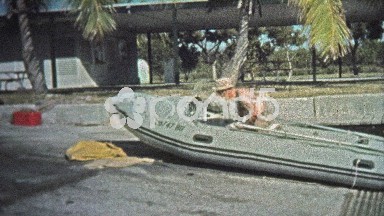 1973: Man driving professional inflatable boat around harbor with pelicans.