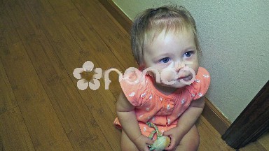 Baby sitting down and looking up at camera.
