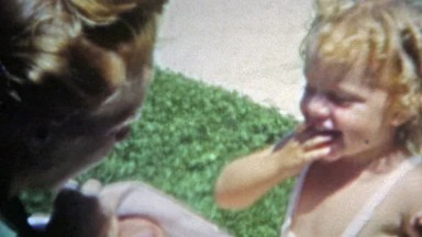 Boulder, Colorado (1951): Mom holding baby while big sister kisses her.