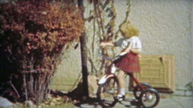 1953: Blonde cute little girls first tricycle ride around the backyard.