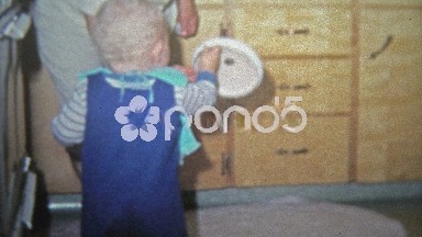 1968: Toddler Boy Playing with Pots and Pans in Kitchen Cabinets