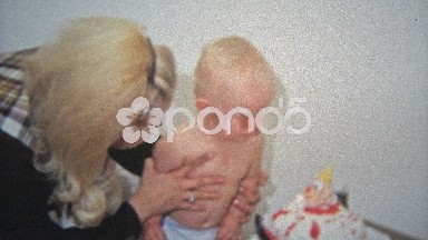 1968: Child first birthday eating cupcake mothers help.