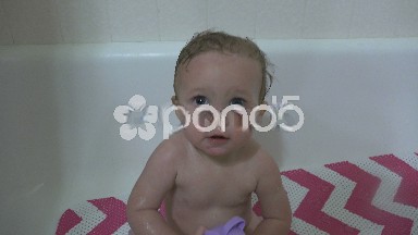 Happy baby taking a bath showing off splash cup toy.