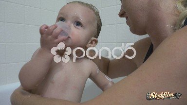 Denver, Colorado, United States: Mom Washing Baby Bath Time While She Eats Something.