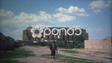1972: Kids Playing Roman Gladiators Near Colosseum Structure with Blue Skies