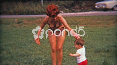 1975: Woman Playing With Son in Park in European Bikini.