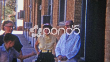 1955: Small town doctor walking with family on main street.