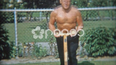 1953: Shirtless man showing off mowing small suburban grass lawn.