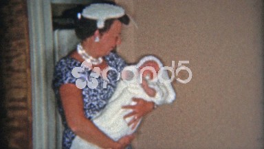 1957: Mother in blue fashion dress holding newborn baby.