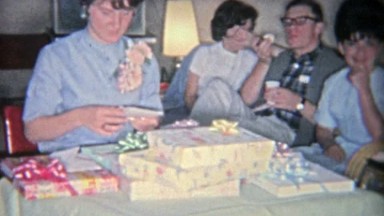 1955: Girl opening sweet 16 gifts from her family and peers.