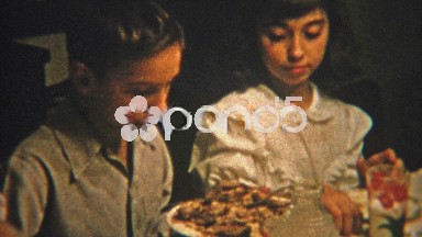 1951: Brother and sister sharing food at the dinner table.