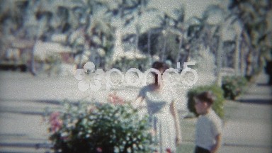 1959: Mom and son of tree lined street as old classic car passes.
