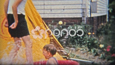 1954: Brother splashing baby boy in kiddie backyard fun pool.