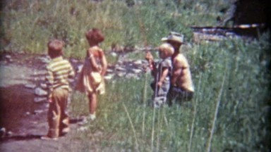 1961: Dad Teaching Kids to Hold Fishing Pole on Grassy Riverbank