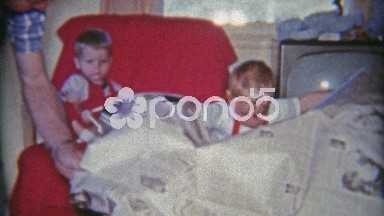 1961: Unwrapping Christmas gift in newspaper of red riding toy horse.