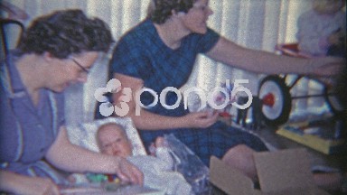 1958: Women Mesmerizing Baby With Butterfly Mobile Toy.