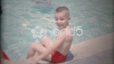 1963: Red swimsuit brothers in public pool playing around edge.