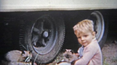 1963: Blonde boy rescues cats trapped under truck tires.