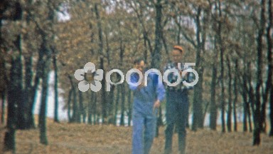 1963: Men throwing horseshoe in autumn leaf forest background