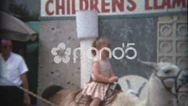 1969: Redhead girl on children's llama ride at amusement park.