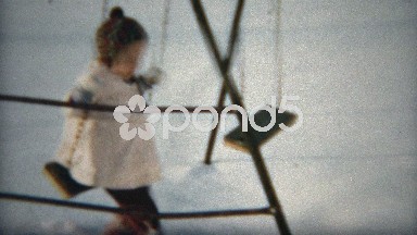 1960: Girl swinging in playground with winter snow on the ground.