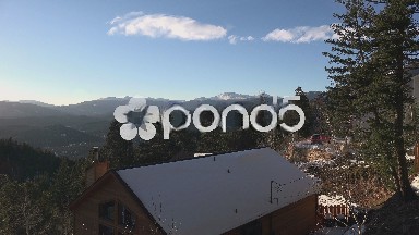 Timelapse mountain top view with snow covered house below from a mega deck.