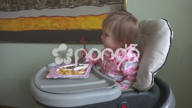 Baby girl eating at a high chair a lunch of gluten free pasta and steak.