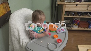 Baby crushing cheerios crunch snacks on high chair playing with food.