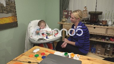 Baby ripping paper towel after painting a mess on mom after creative project.
