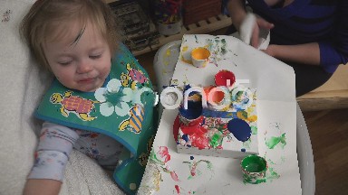 Mom helping baby finger paint art dripping paint on canvas creates smiles.