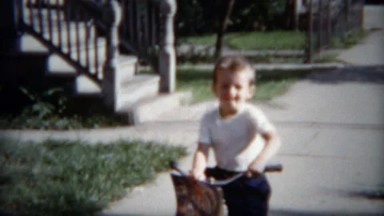 1953: Boys practicing bike riding on residential city sidewalks.