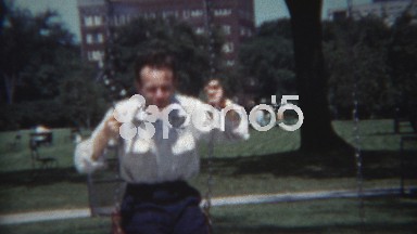 1954: Dad swinging in city playground showing off for his son.
