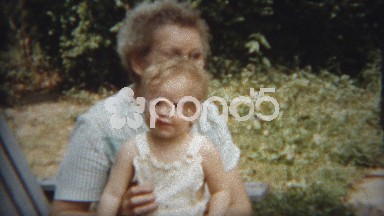 1954: Calm sage grandma holding new blonde baby girl getting smiles.