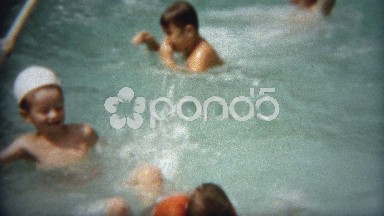 1956: Boys playing poolside polo ball throwing at friends.
