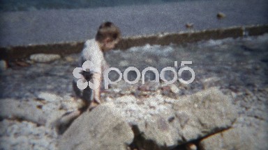 1954: Boy exploring a water seawall holding back the crashing waves.