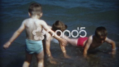 1954: Kid brothers in colorful neon swimsuits playing on the rocky beach.