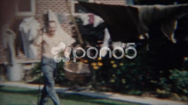 1956: Two Person Saw Carried Through Front Yard Shirtless Caucasian Man.