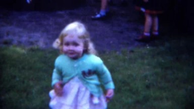 1953: Cute blonde toddler running wild eating hotdog at summer picnic. PITTSBURG