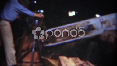 1949: Man working giant motorized saw to cut tree logs industrial lumber mill.