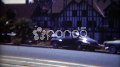 1949: Parked cars on the road in front of tudor architecture style mansion