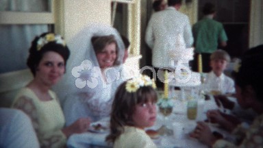1966: Wedding reception party groom and bride kiss at outdoor table.