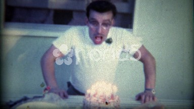 1963: Nerdy eyeglasses wearing wild man blows out birthday cake candles. PLANO,