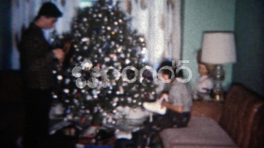 1962: Siblings get ice skates for holiday gift in front of Christmas tree.