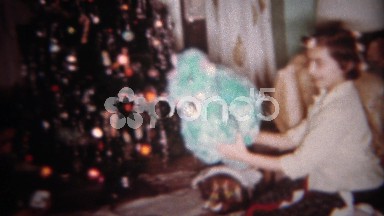 1962: Girl in hair curlers opens stuffed animal toy at Christmas tree. BUFFALO,